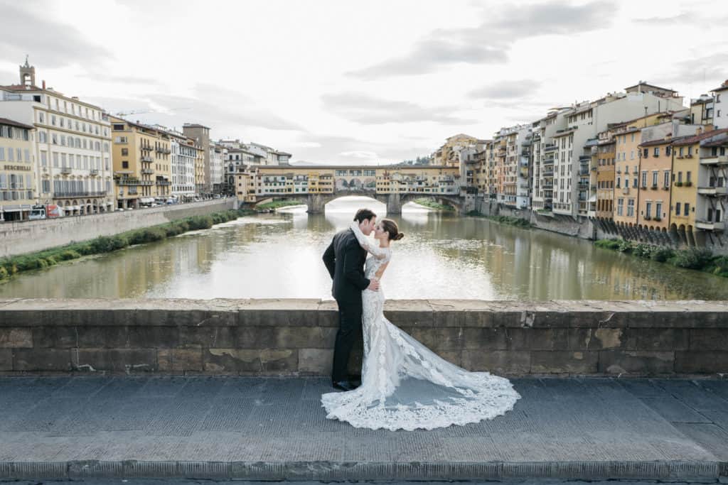 The groom and the bride kissing in front of Ponte Vecchio, one of the most famous monument in Florence