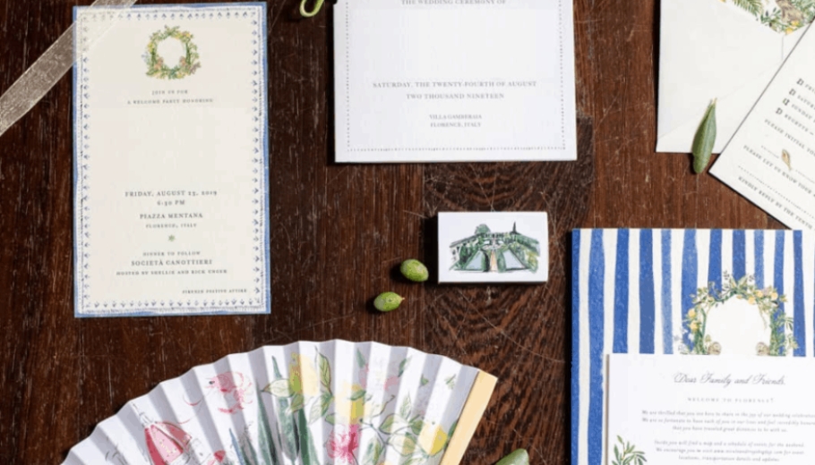 A table set with wedding invitations and two fans, illustrating a theme for booking a wedding in Italy.