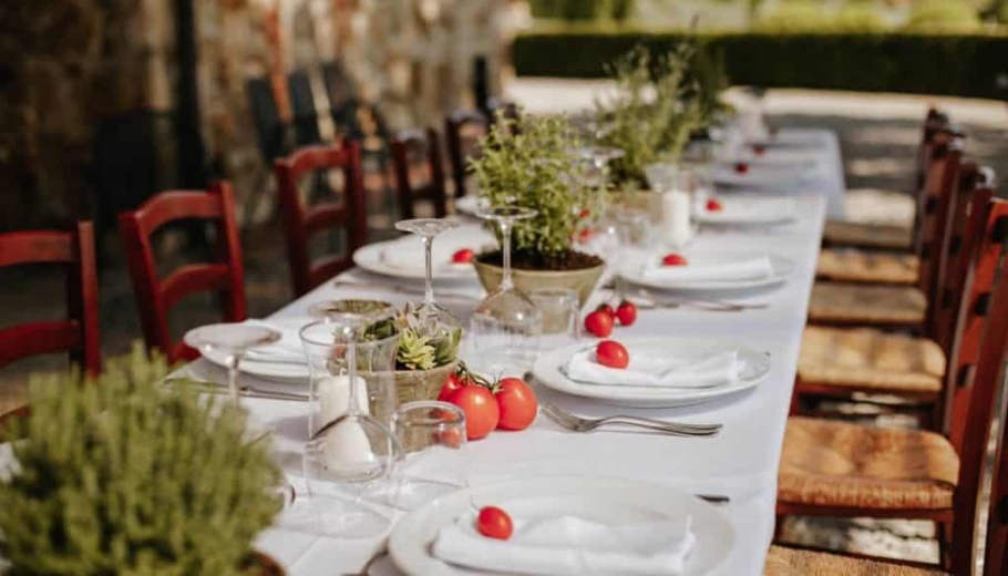 A beautifully arranged long table with a white cloth and vibrant red and green plants, perfect for exclusive weddings in Italy.