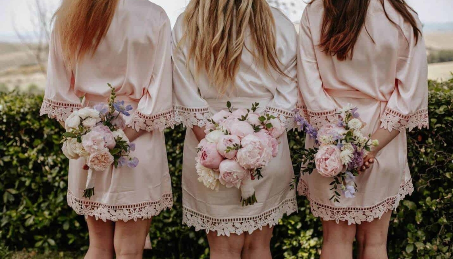 Bride and her girlfriends standing back with wedding dresses and buttercup flowers