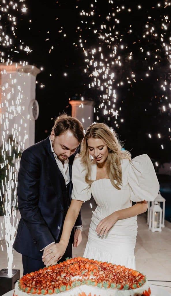 The bride and groom cut the cake on the background of fireworks