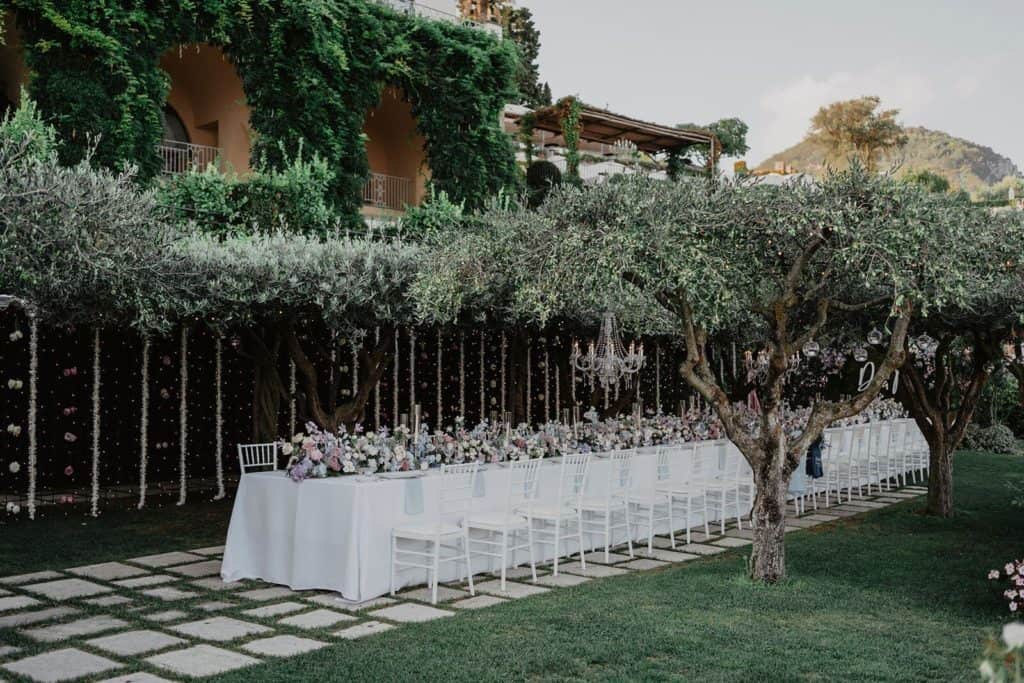 Decorated table for a celebration in the garden of the villa, surrounded by green trees