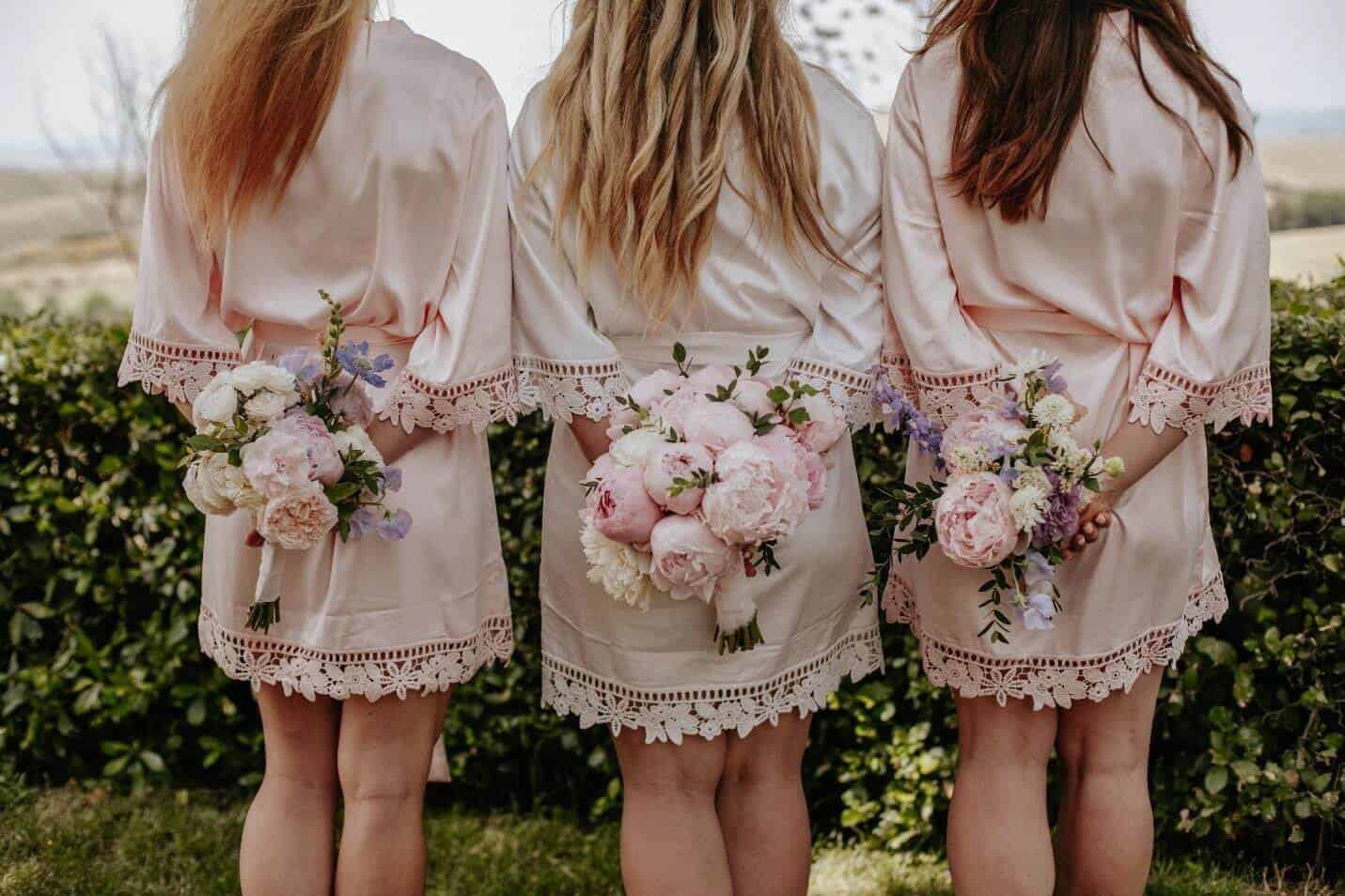 Bride and her girlfriends standing back with wedding dresses and buttercup flowers