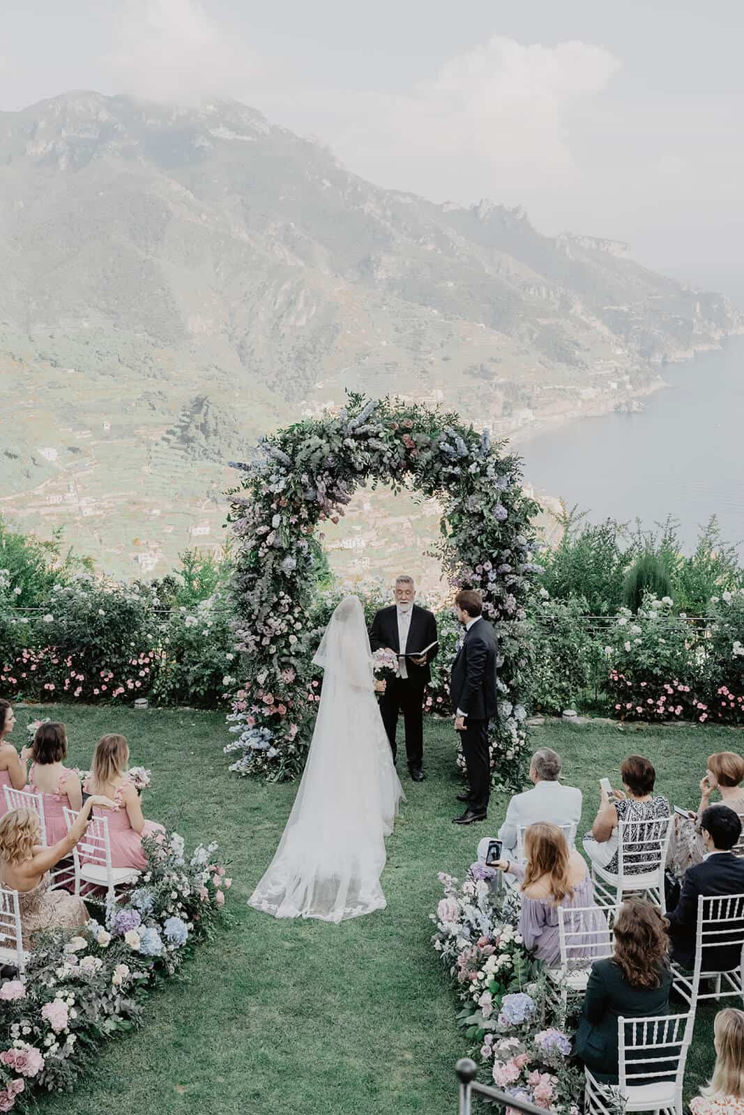 bride and groom at their garden wedding with an archway full of seasonal flowers