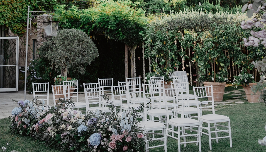 Garden wedding setup at Hotel Belmond in Tuscany, showcasing floral arrangements and seating for a Catholic Italian ceremony.