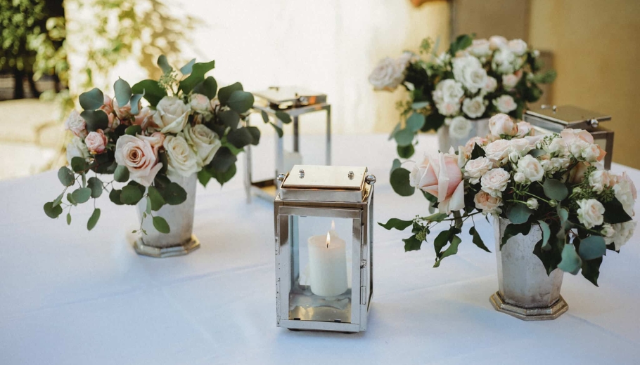Metal lanterns filled with pink and white wedding flowers, set on a gift table glowing with candlelight.