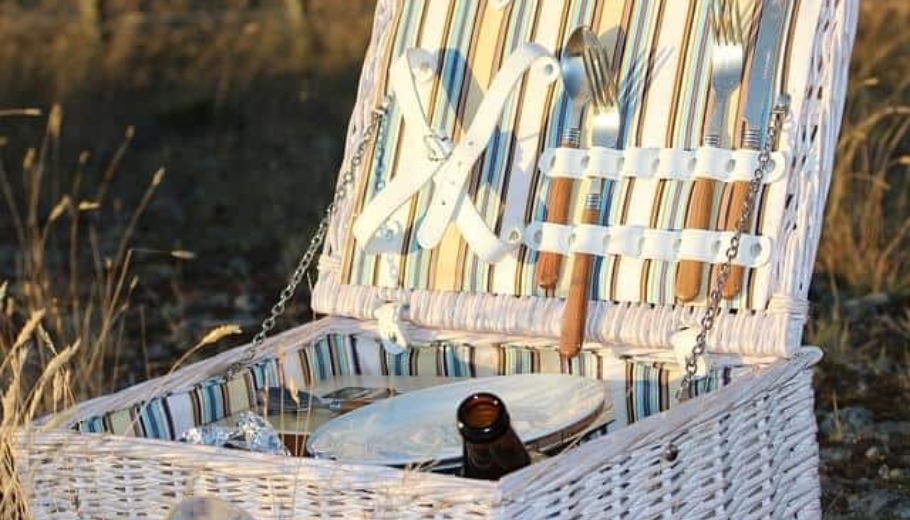 A picnic basket containing a bottle of wine and a knife, symbolizing a romantic setting for a marriage proposal.