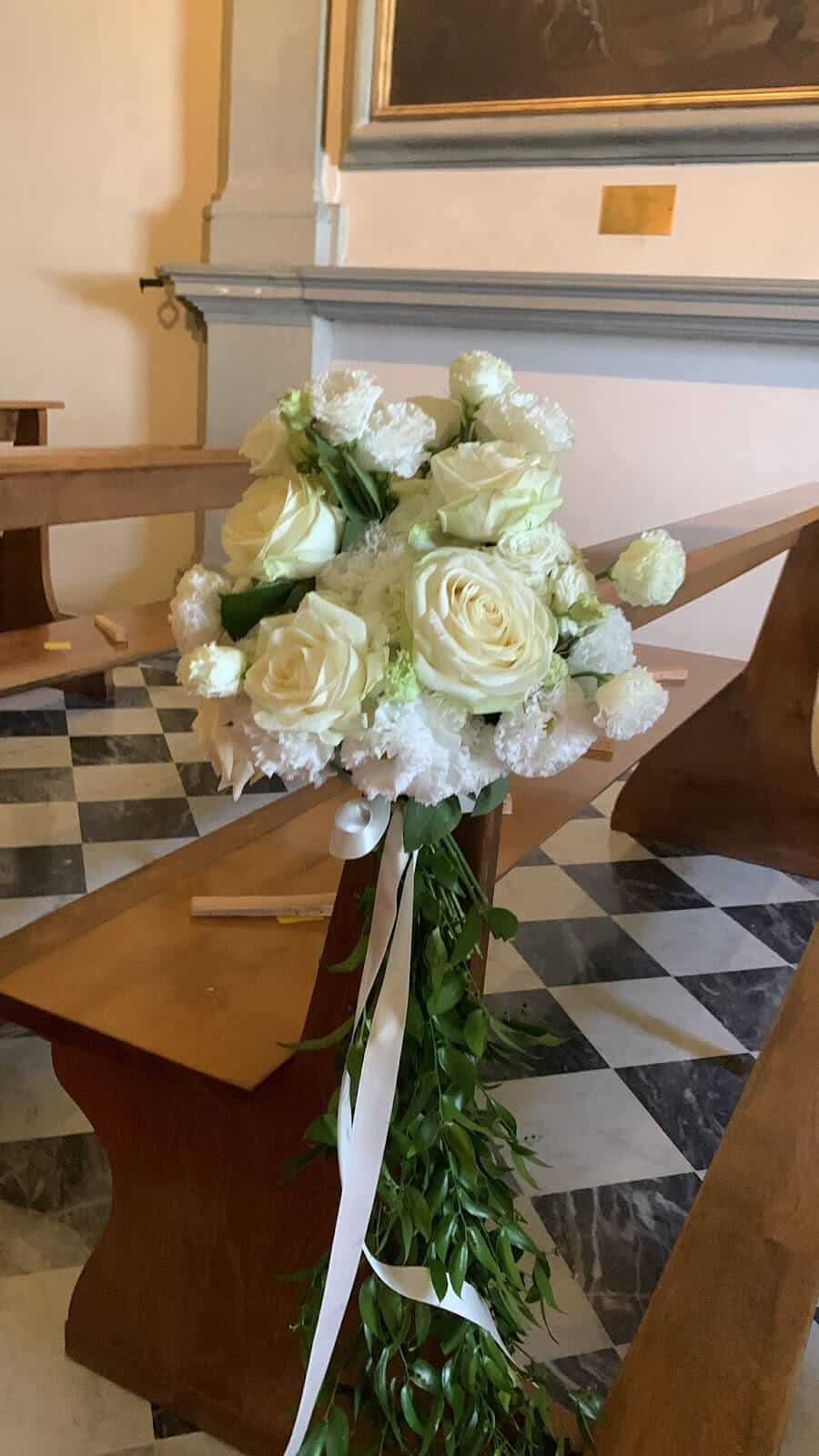 Inside church bench with flowers for a Catholic Wedding In Italy