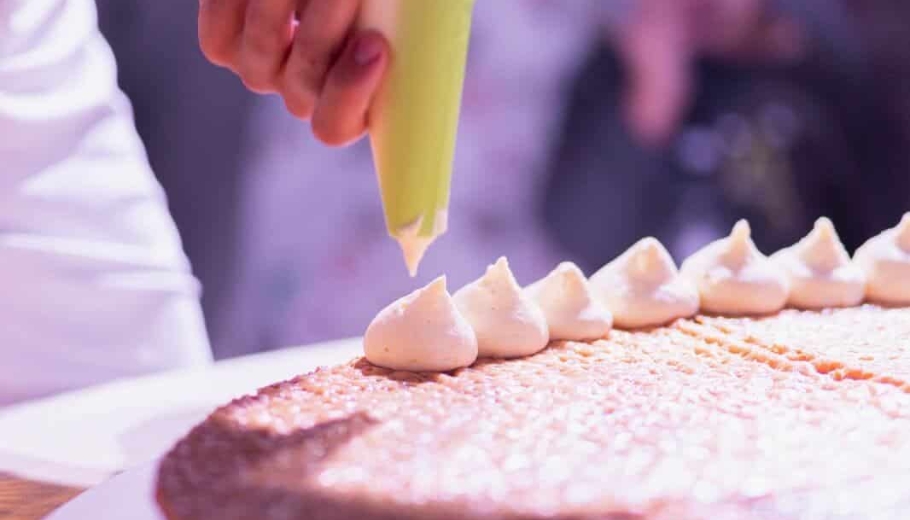 italian chef is decorating a wedding cake
