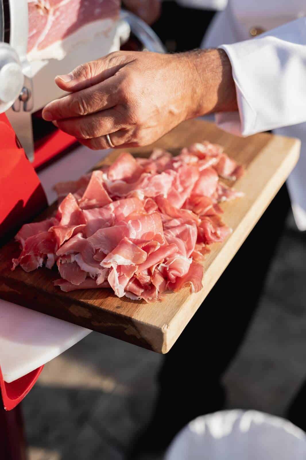 Italian chef is cutting prestogious raw ham for the wedding menu 