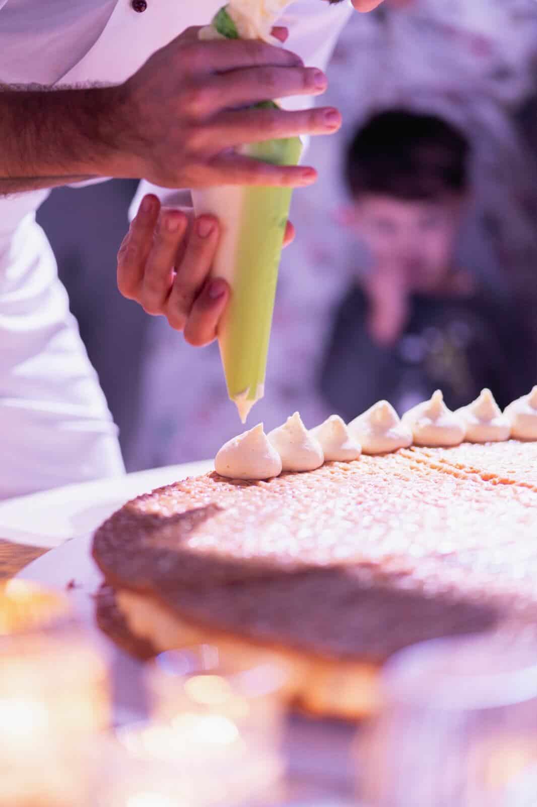 italian chef is decorating a wedding cake