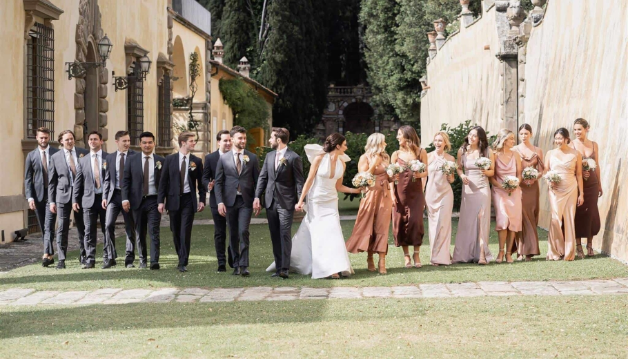 A wedding party poses joyfully for a photo in front of a beautiful building, celebrating their special day together.