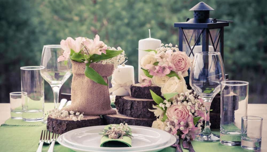 A wedding table setting featuring a black lantern entwined with flowers, surrounded by candles for an elegant ambiance.