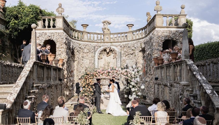 A newly married couple joyfully exits the wedding aisle as guests celebrate.