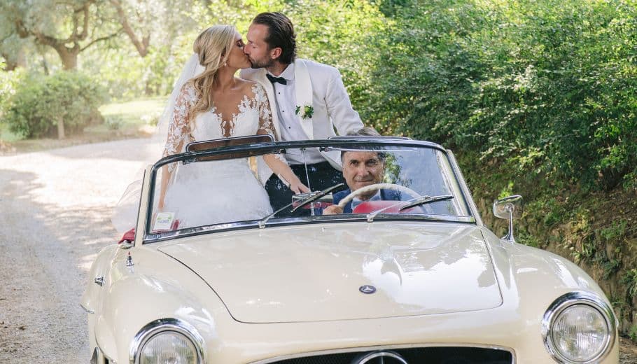 Bride and groom kiss in a vintage car, embracing their Italian wedding adventure.