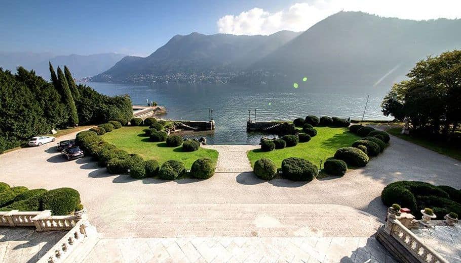 Beautiful garden landscape at Villa Erba, with a calm lake and stunning mountains providing a breathtaking backdrop.