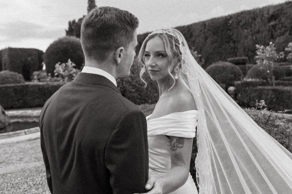 Newlyweds share a heartfelt gaze in a classic Italian garden, surrounded by lush greenery.