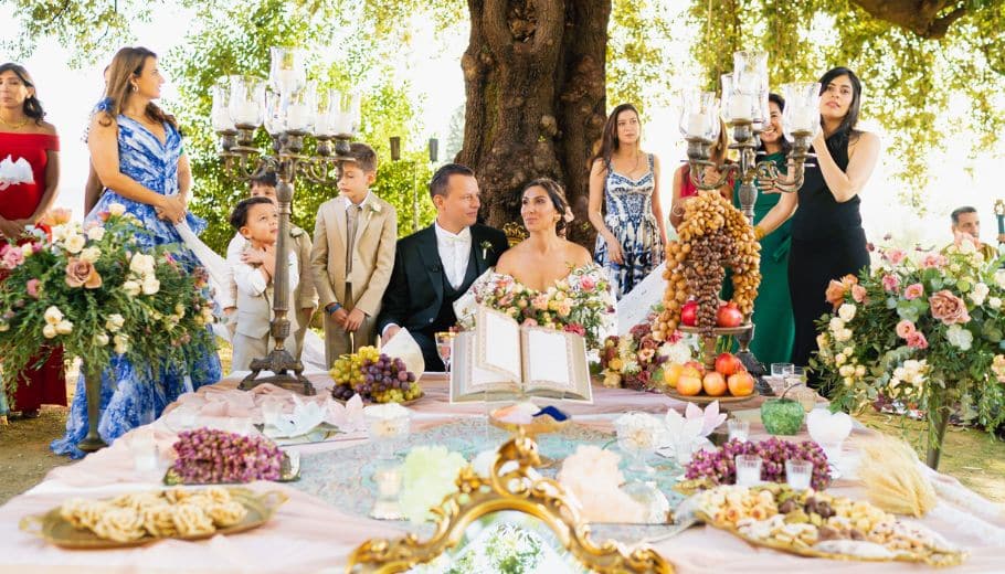 Italian outdoor wedding with guests seated around a culturally decorated table.