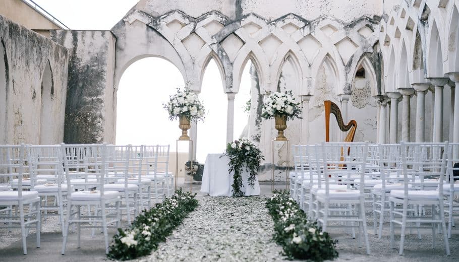 Scenic Amalfi Coast wedding setup with white chairs and colorful flowers, perfect for an outdoor ceremony.